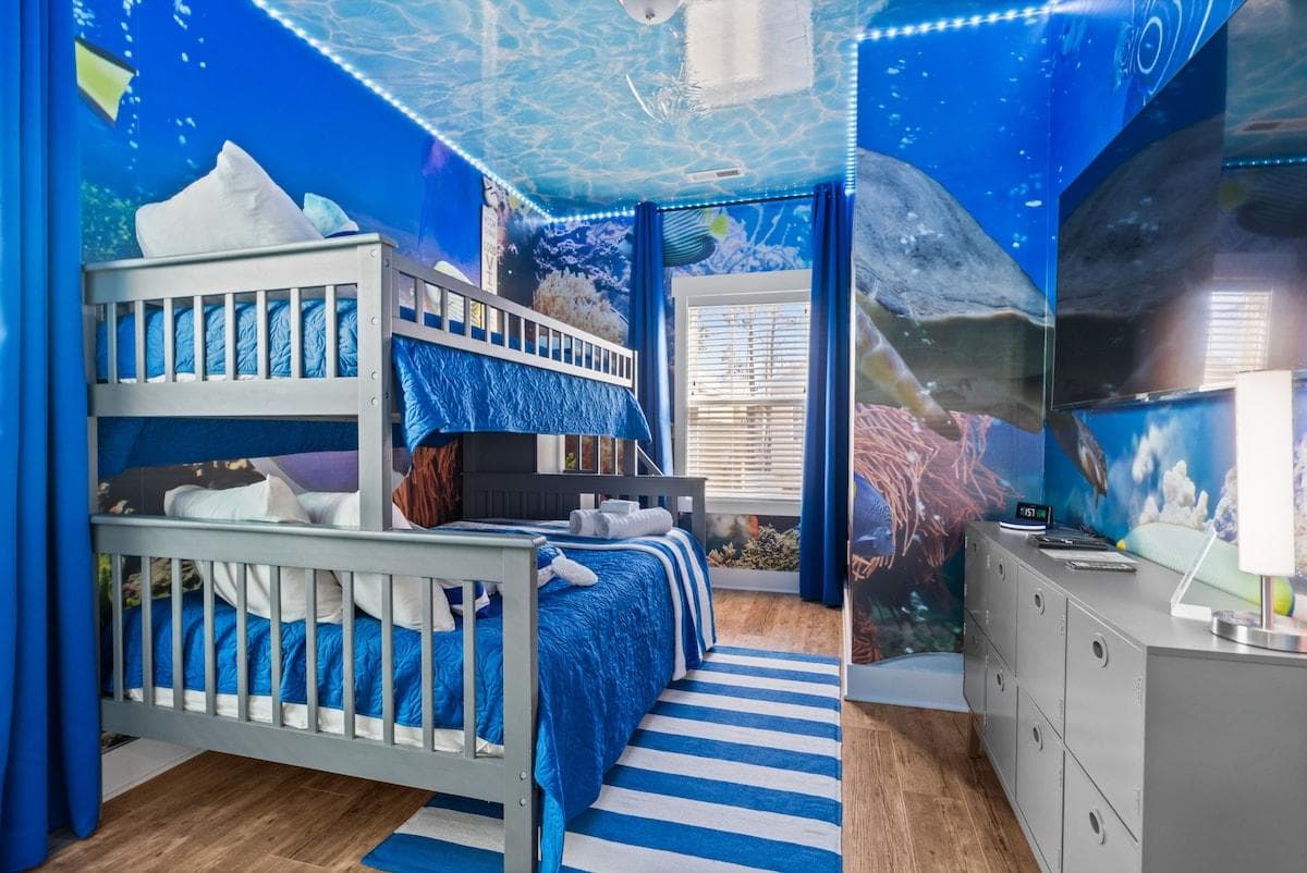 Discover a captivating underwater world in our Immersive Aquarium Bedroom located on the 2nd floor. A bunkbed (twin over full) nestles among LED lights and vibrant aquarium-themed wallpaper. Complete with a 55" TV, it's a marine escape for kids.